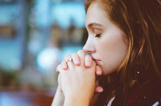 A young woman with her eyes closed in prayer