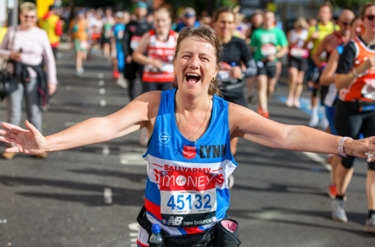 Woman running and smiling in Sally Army vest