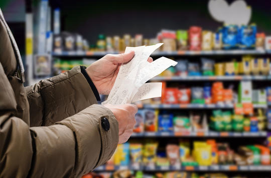 a man holding a receipt from a supermarket 