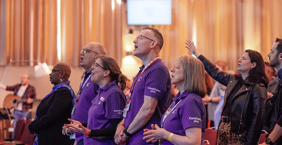 Close shot of officers in purple candidates unit shirts singing in worship.