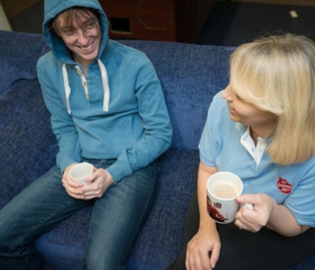 Salvation army officer and client drinking tea