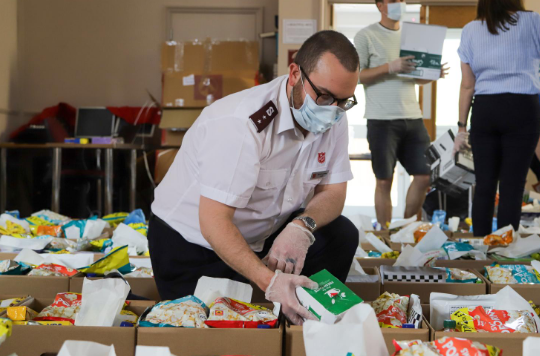 Salvation Army officer wearing a face mask packing food parcels