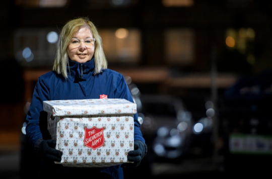A Salvation Army volunteer with a Christmas parcel
