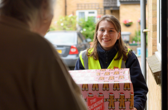 A Salvation Army volunteer with a Christmas parcel
