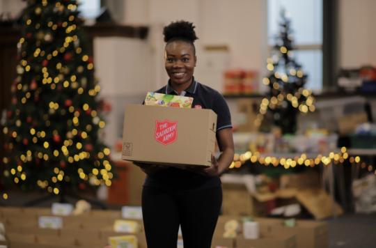 Salvation Army volunteer carrying a Christmas hamper