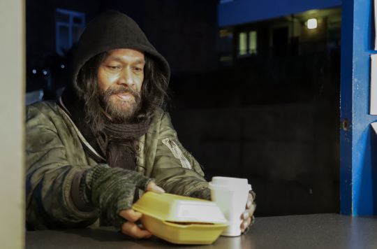 A homeless person being served a hot meal