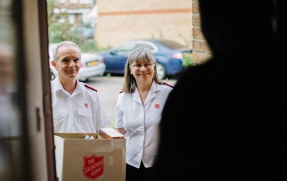 Salvation Army Officers delivering a food parcel.