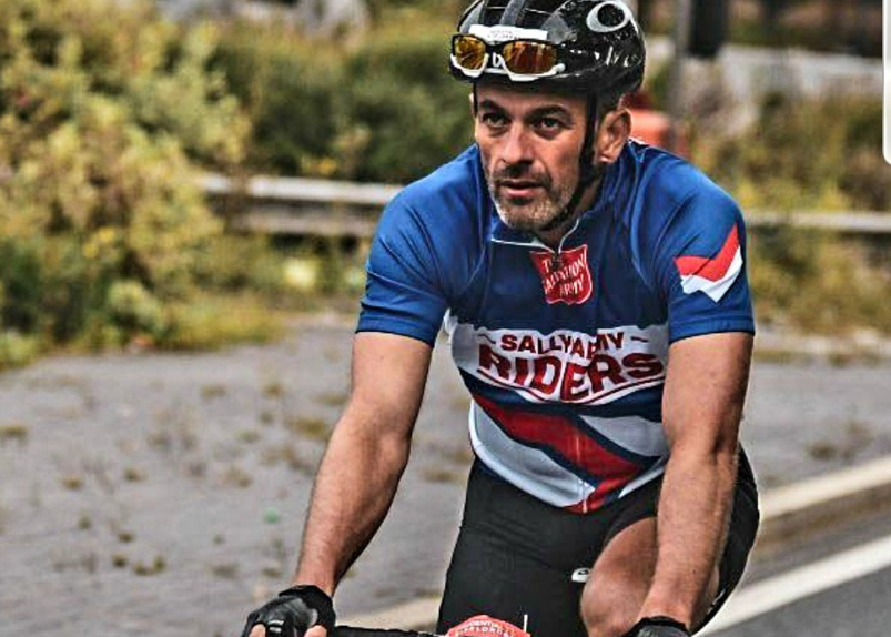 Man riding bike with Sally Army vest 