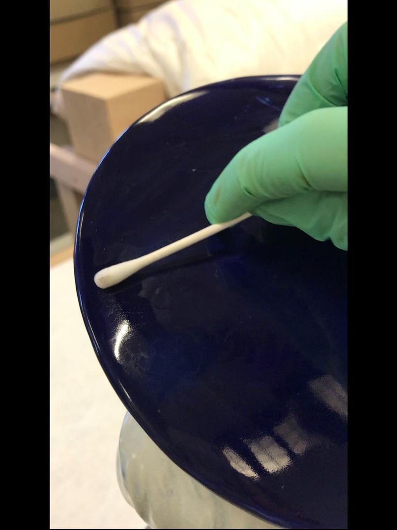 Cleaning ceramic bust with a cotton swab