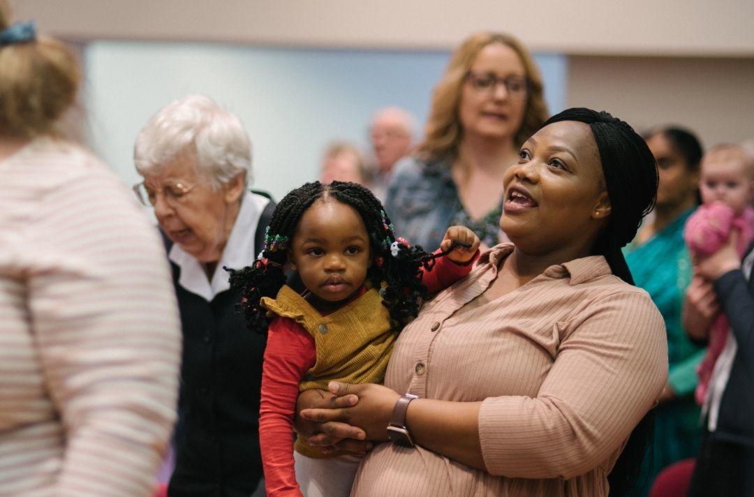 a woman holding her daughter in a crowd of people at a Salvation Army church