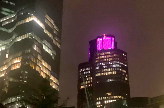 Tower 42 in London lit up at night with the Salvation Army shield 