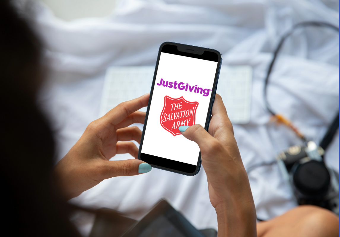 Hands holding a smart phone showing the JustGiving and Salvation Army logos on the screen