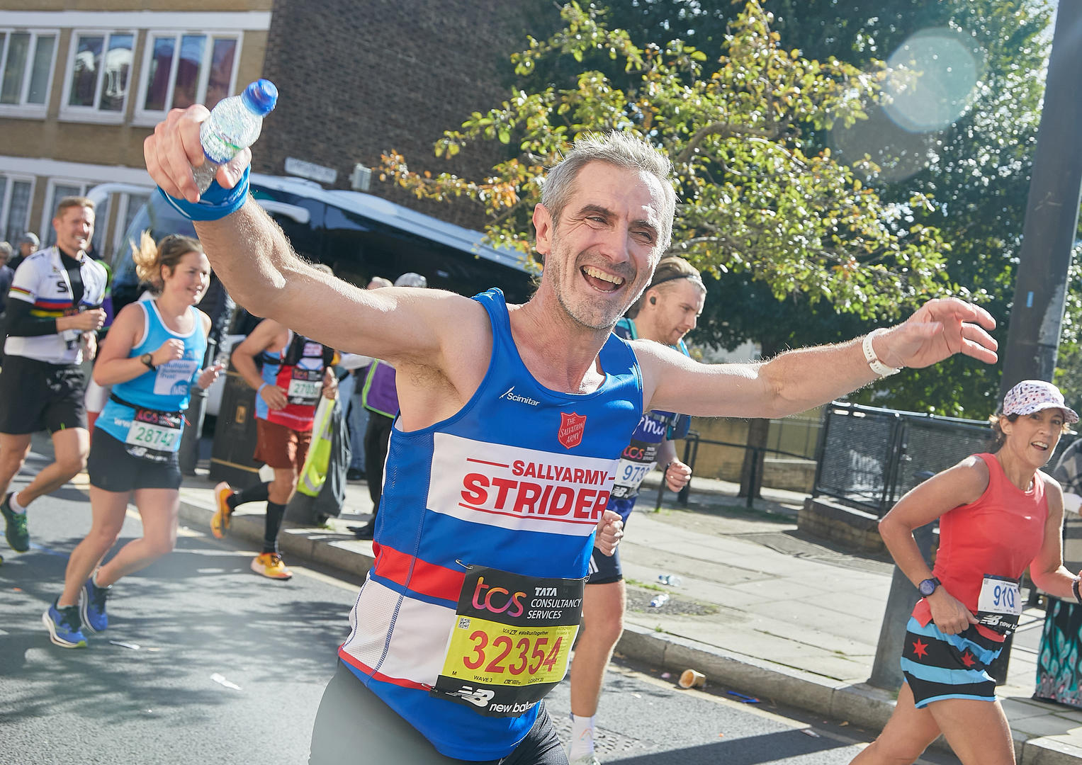 Man cheering as he runs the London Marathon wearing a Team Sally Army vest