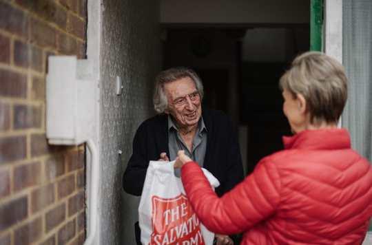 A Salvation Army volunteer brings an elderly gentleman a care package.