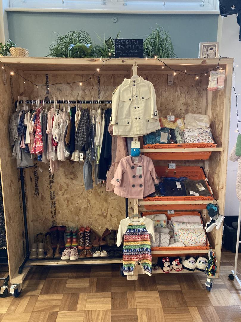 Image of clothes on a rail at our baby wardrobe event. Shows some really beautiful clothes as well as bundles of clothing.