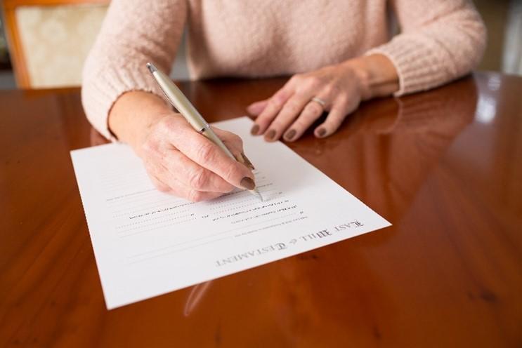 A female sitting at a table writing a will 