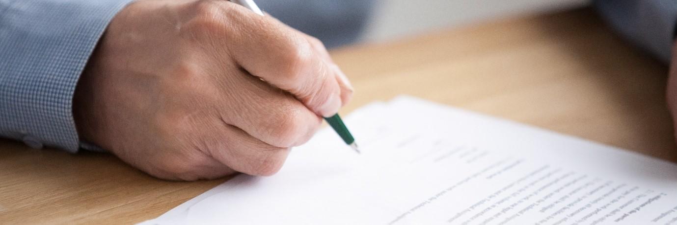 An image of someone writing a will with a pen in their hand