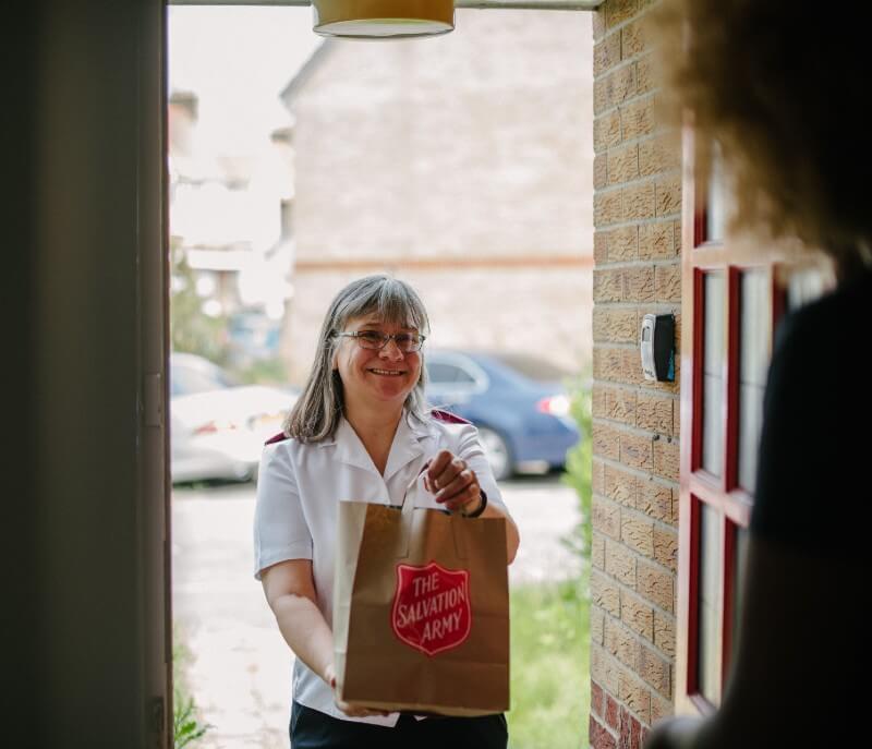 Salvation Army Officer delivering a parcel to a family's doorstep