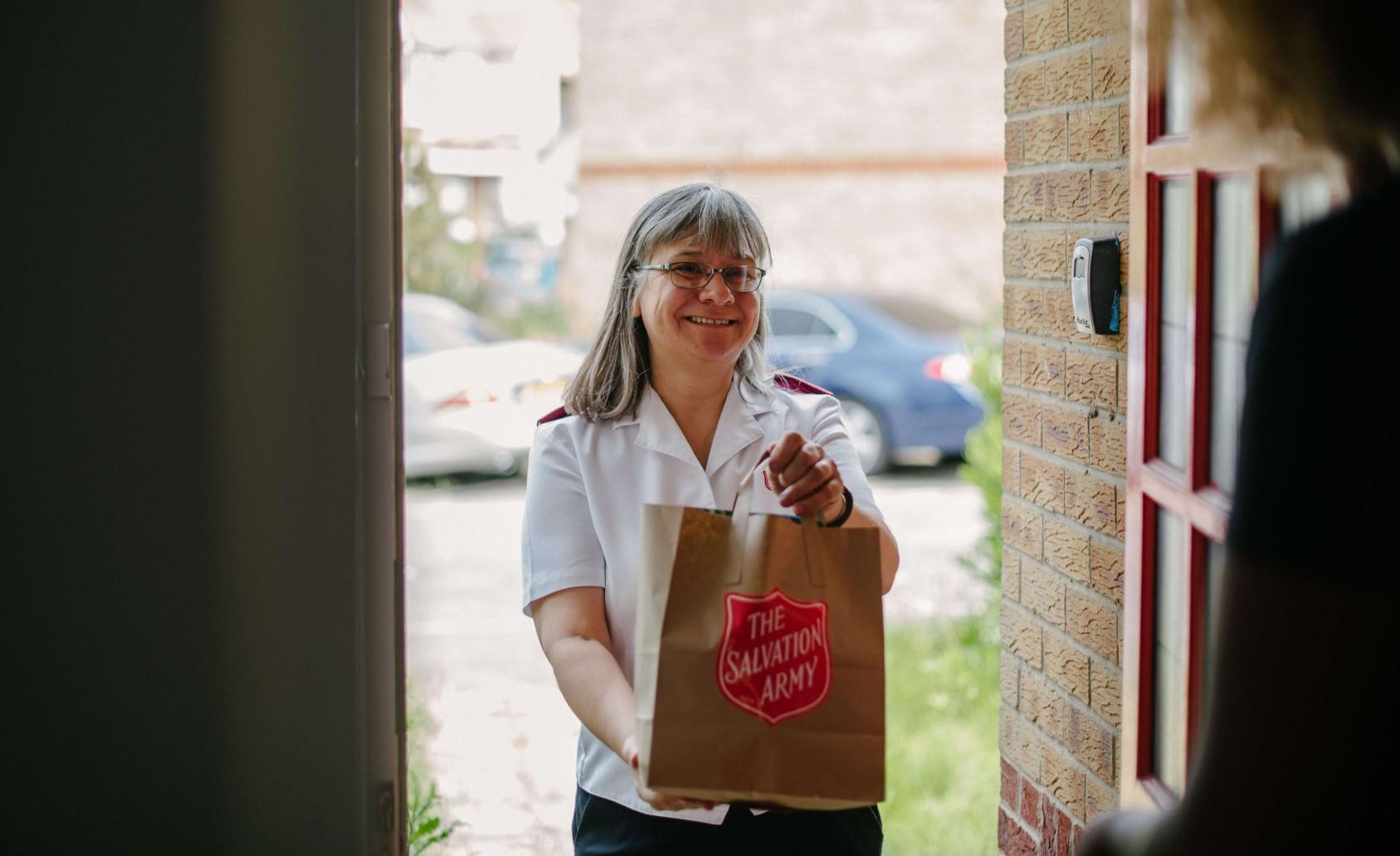 Salvation Army Officer delivering a parcel to a family's doorstep