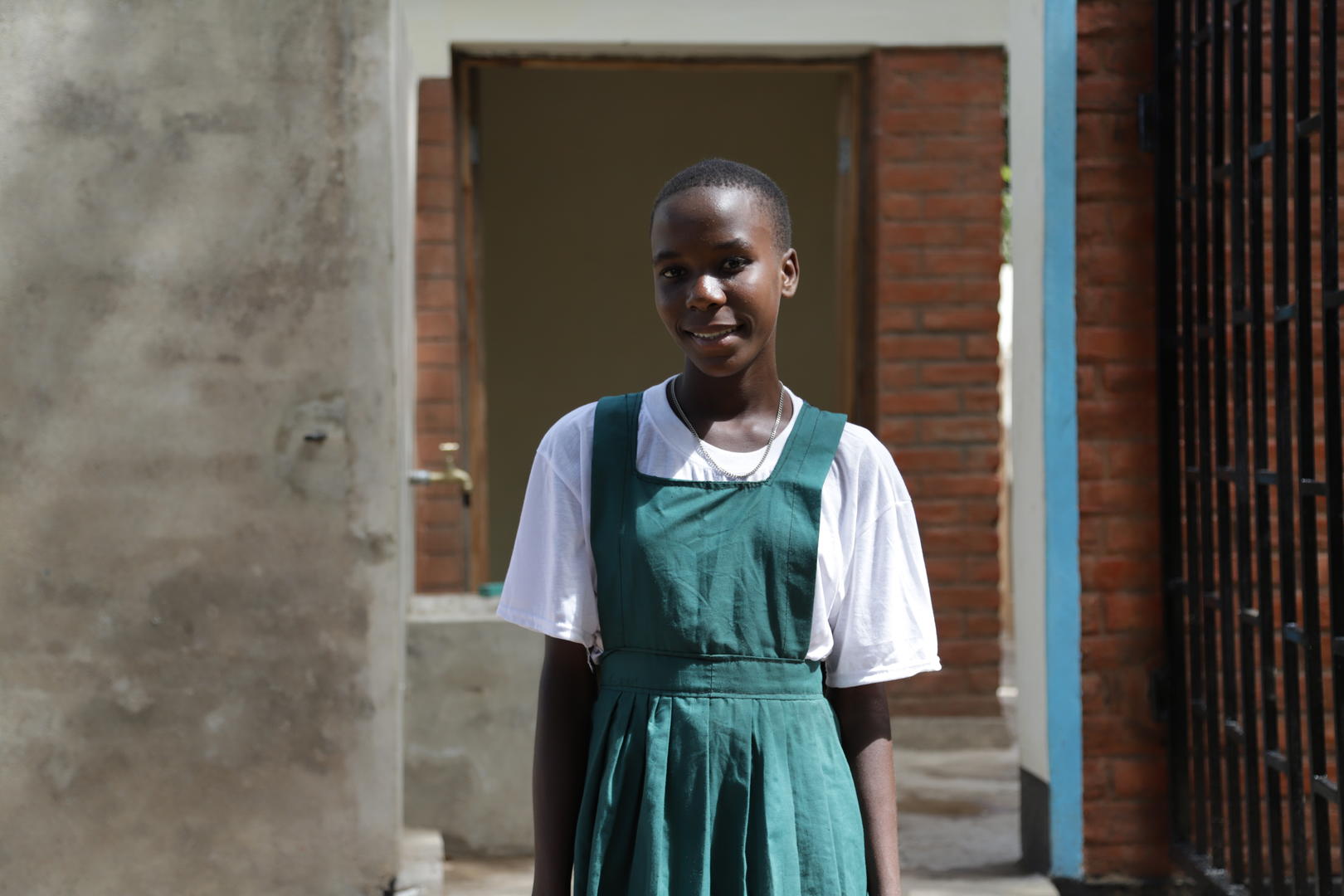 Mary, a young black girl, stands smiling at the camera