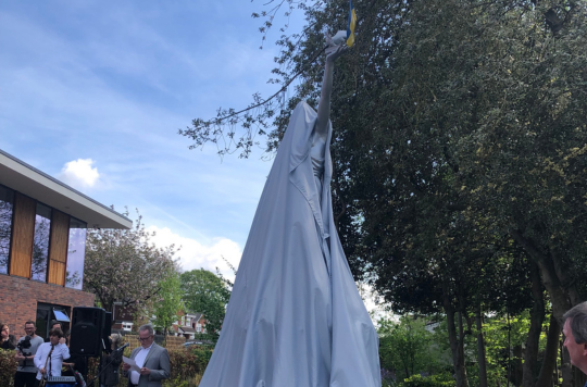 A statue of a person covered at an unveiling