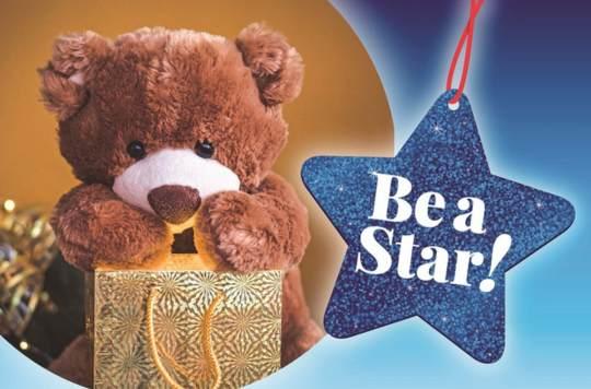 a little brown teddy bear holding a small gift bag next to the big blue star logo for the Be A Star Christmas present appeal