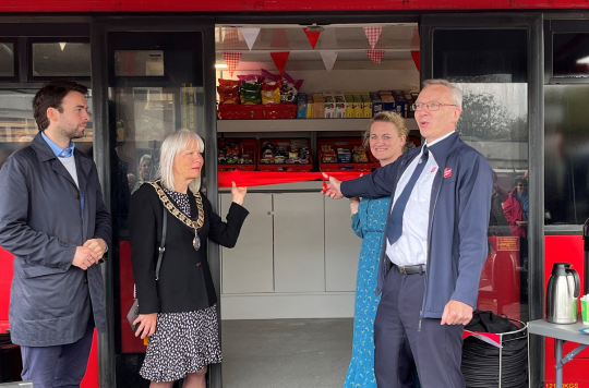 From left to right: Andrew Forsey, Louise McKinley, Elaine Harvey, Howard Russell, are stood in the door way of the double decker bus and cutting a red ribbon