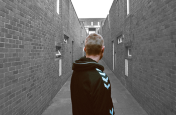 A man, James, with his back to the camera, standing in an alley way.