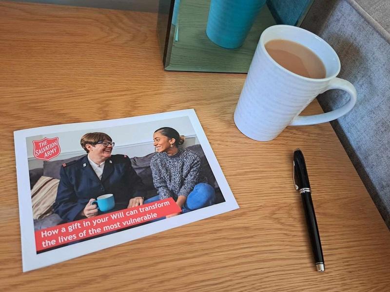 a copy of The Salvation Army's Free Will Guide on a table with a hot cup of tea and a pen beside it. 