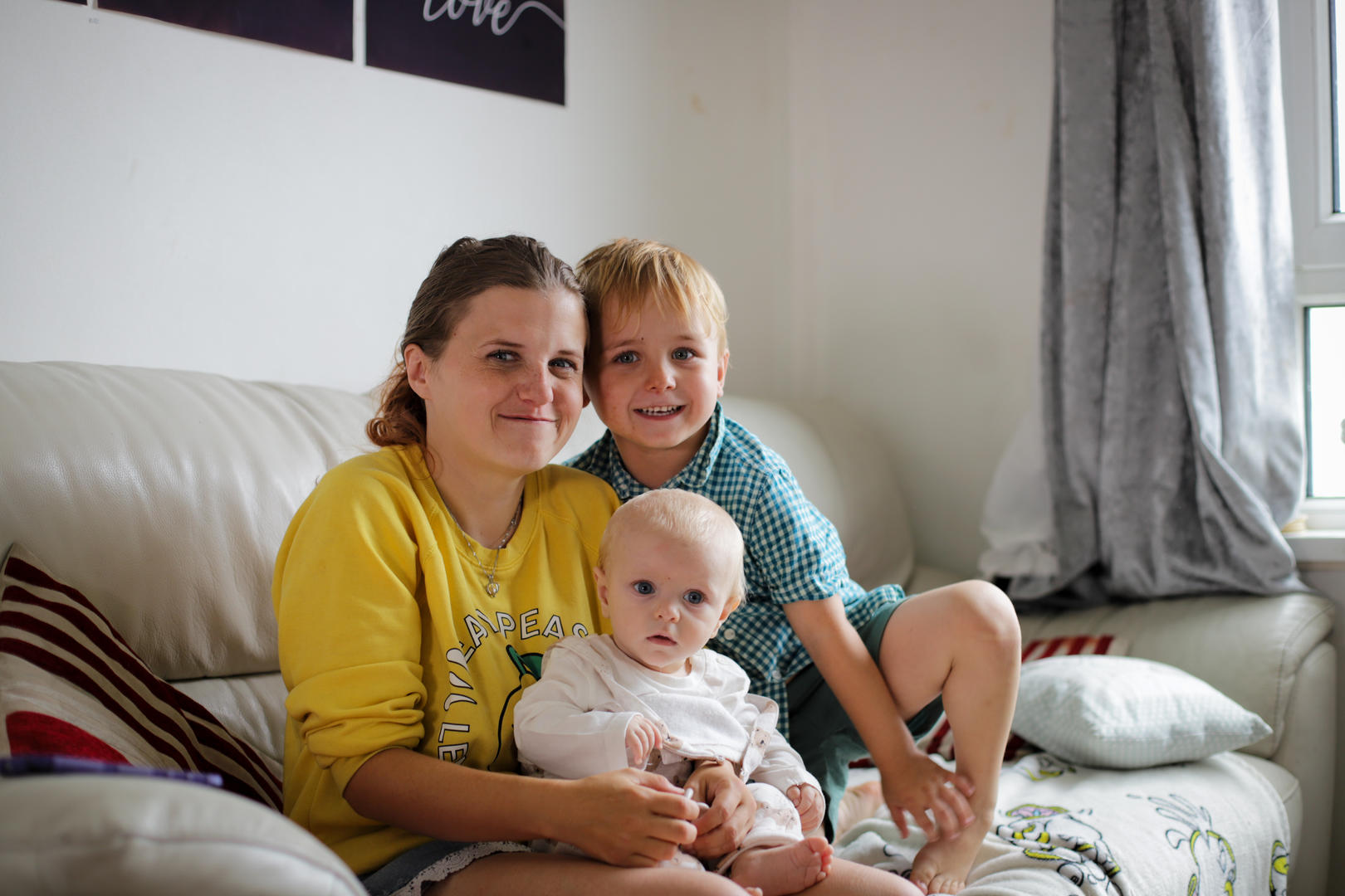 Woman sitting on a sofa with her two small children both who are smiling