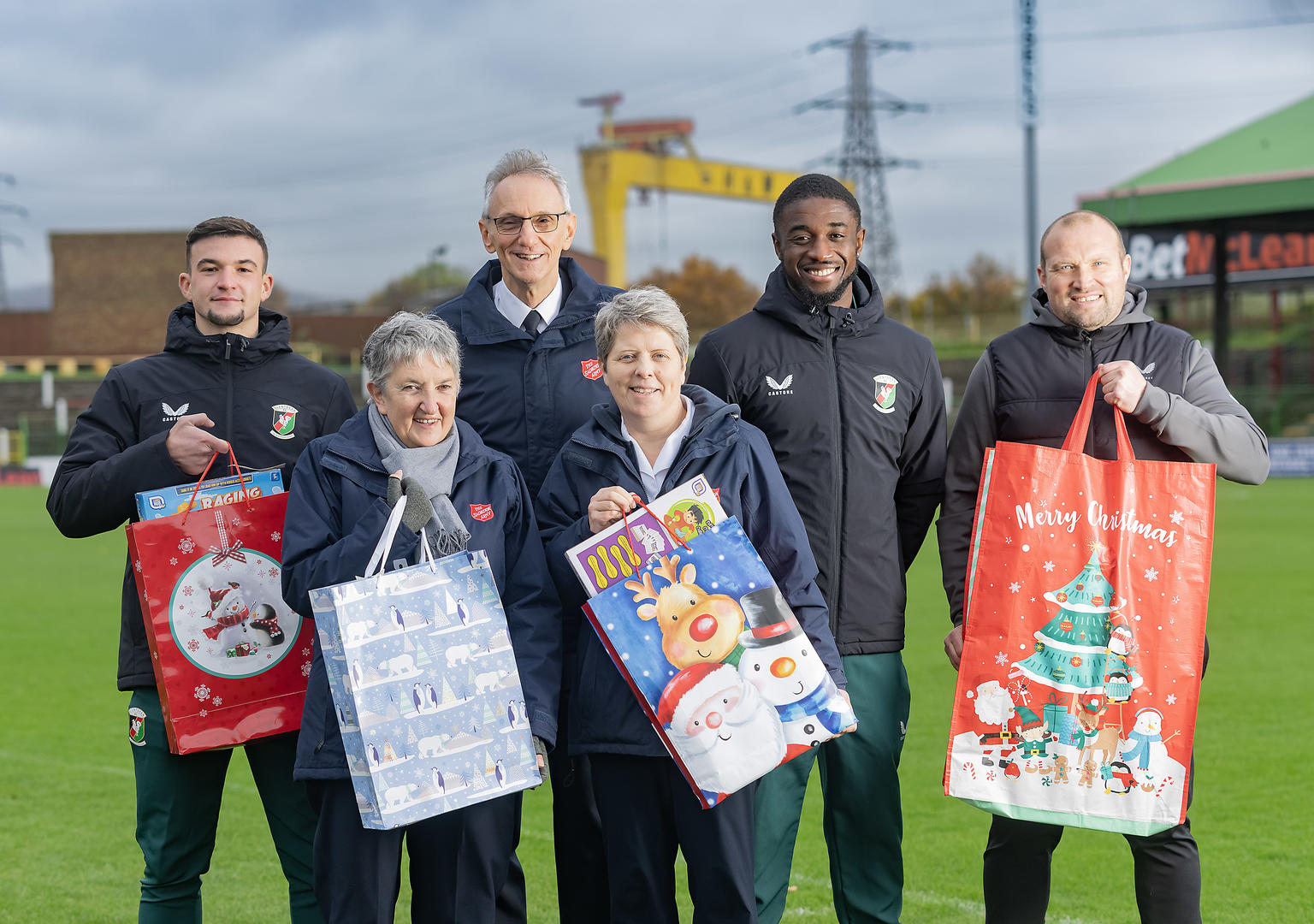 Members of Glentoran Football Club with Salvation Army Officers holding Christmas toys in gift bags.