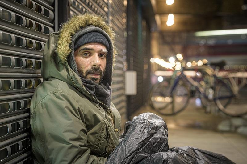 A homeless man is pictured at night sitting on a street