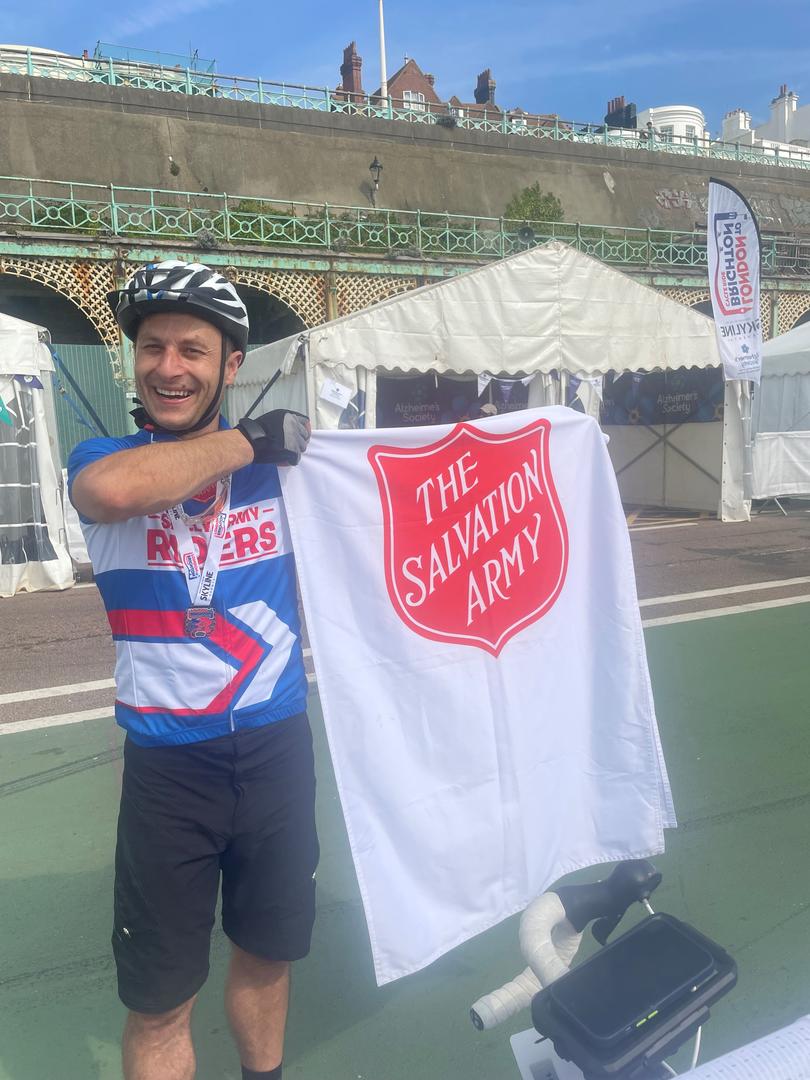 Man wearing Salvation Army cycling jersey holding flag