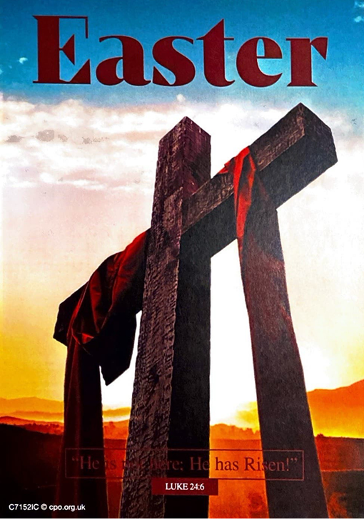 A cross with red fabric draped over it in the foreground and the background of a sun setting sky over hills.