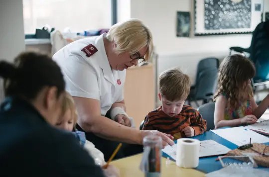 A salvation army worker helping a child to draw