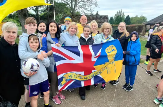 A group of people holding a Ukrainian and UK flag 