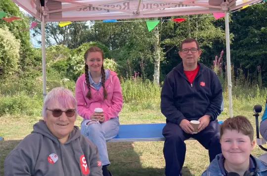 A group of people smiling at the camera in a Salvation Army gazeebo 