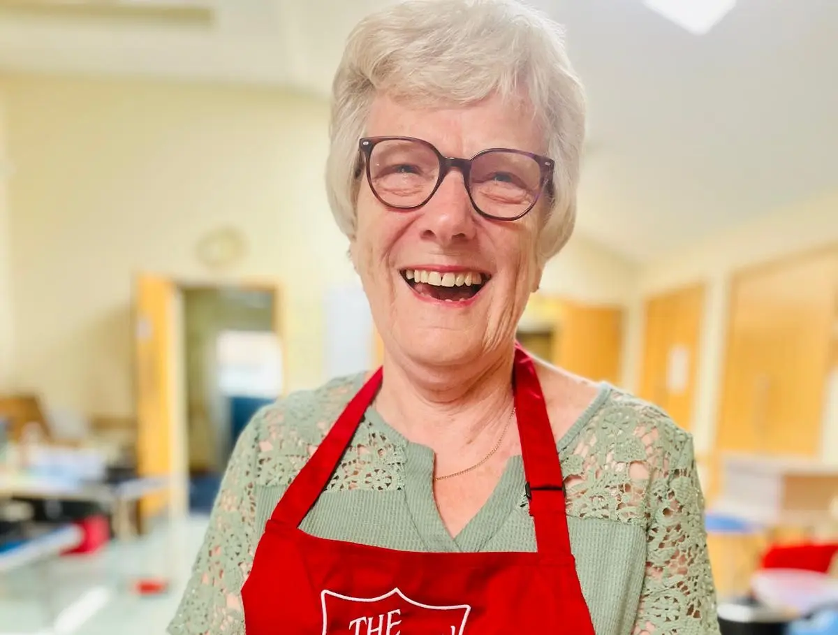 A woman smiling towards the camera, wearing an apron.