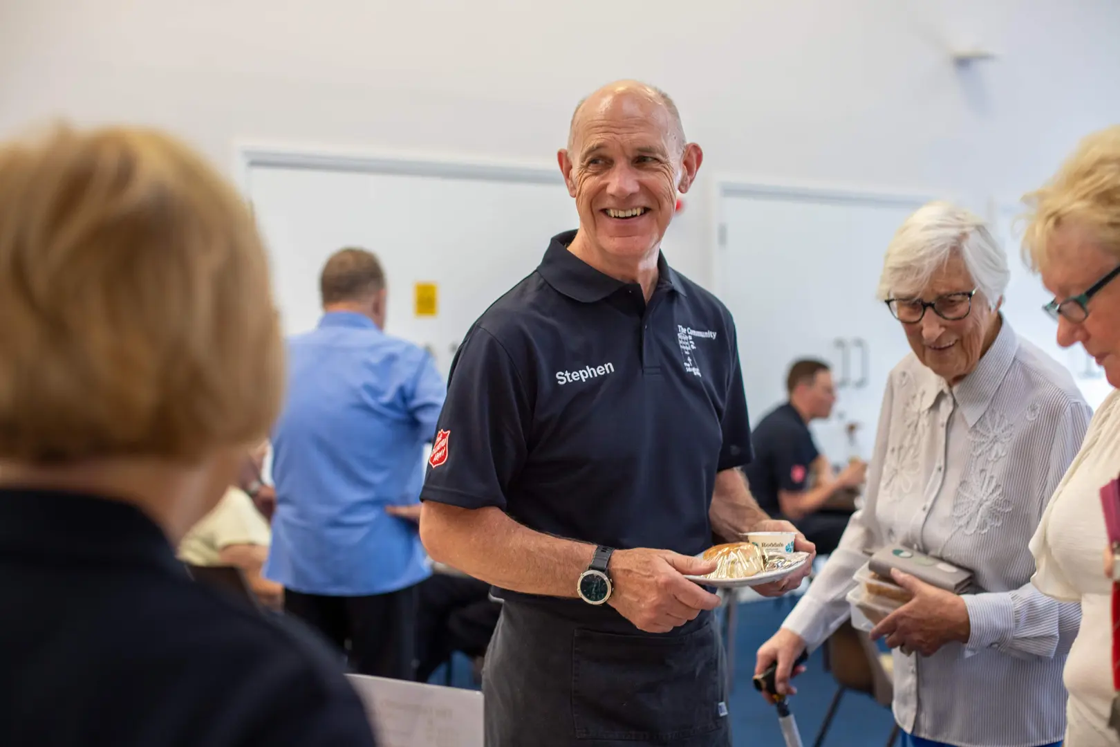 Man smiling cheerfully at the camera, wearing a Salvation Army top.