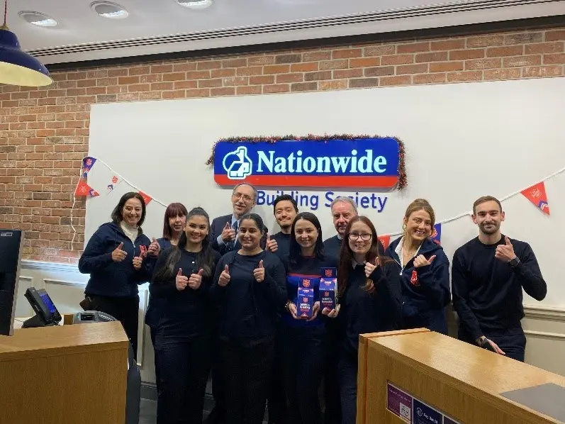 A group photo of the employees at Nationwide St. Albans branch all giving a thumbs up accompanied by two members of The Salvation Army fundraising team.