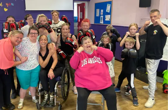 A group of people wearing boxing gloves and smilng 