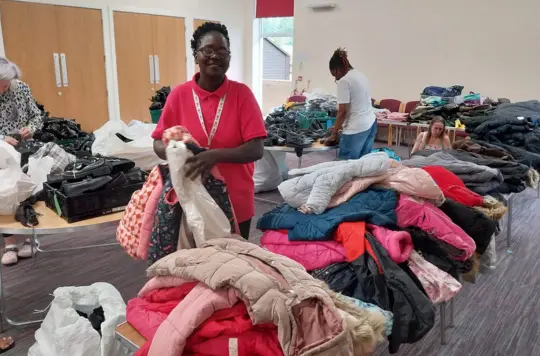 A woman stands with items of clothing on tables 
