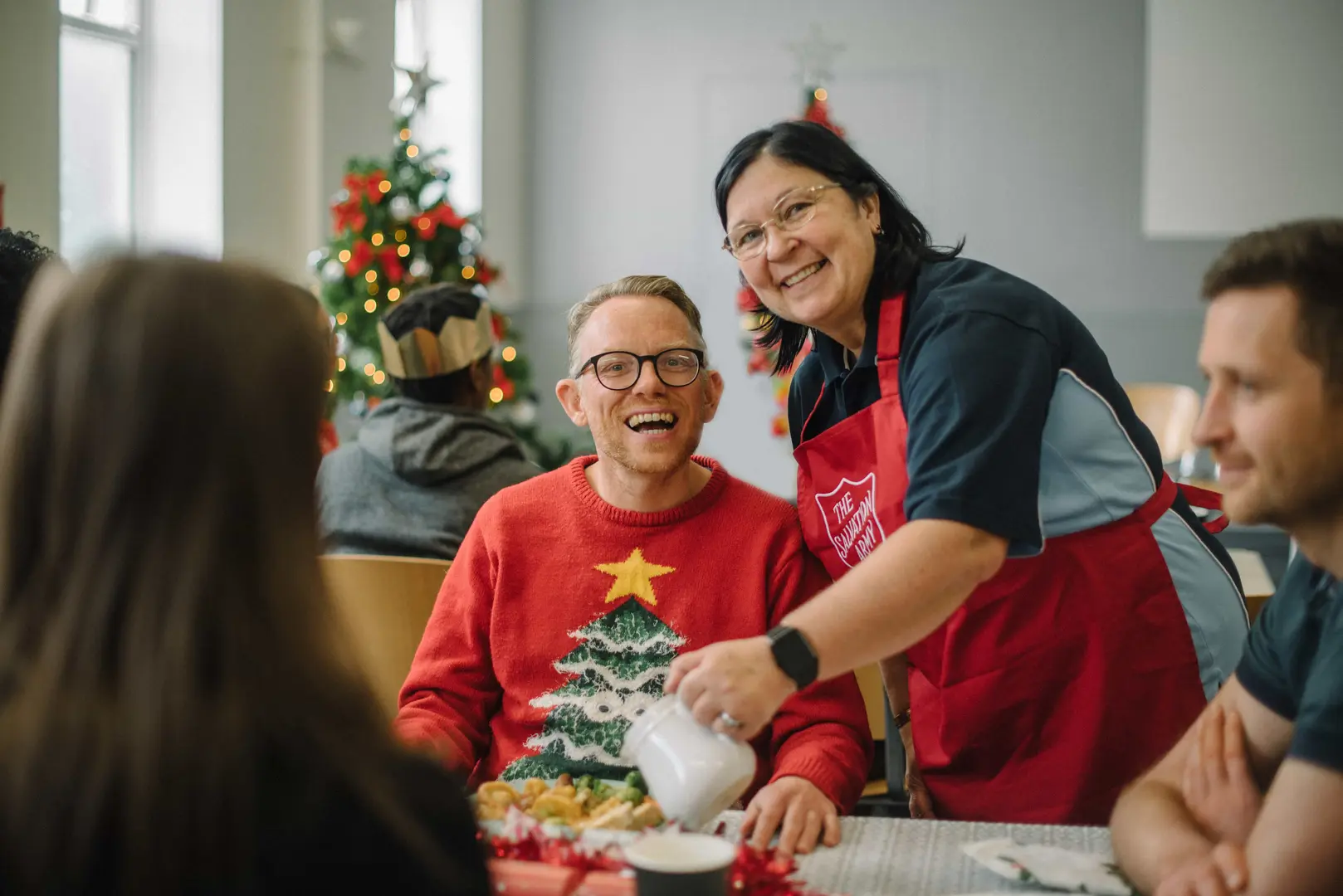 A man being served food by salvation army staff, both look very happy and festive.