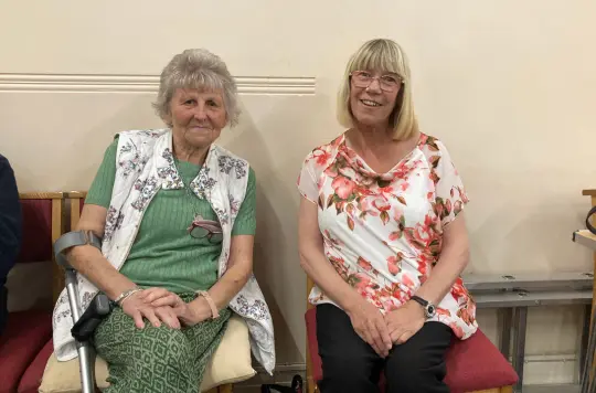 Two woman sitting and smiling at the camera