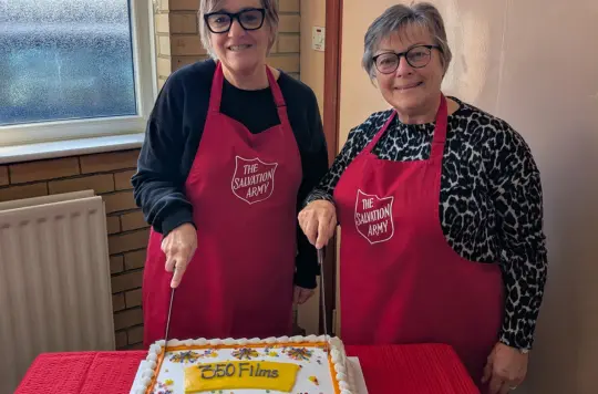 Two Salvation Army volunteers pose with a 350th cake 