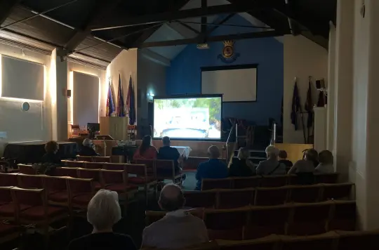 People in a Salvation Army hall showing a film on a big screen 