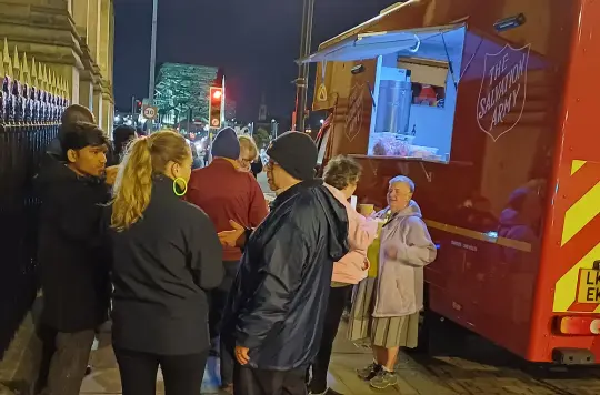 A group of people talking beside Salvation Army Emergency Response vehicle