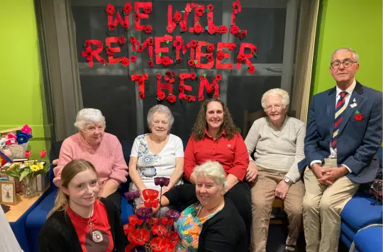 A group of people sitting in front of a Remembrance display 
