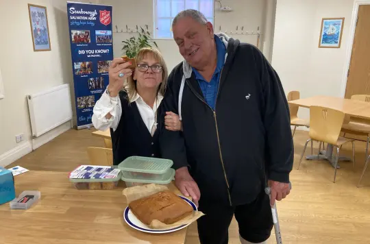 Two people smiling beside a ginger loaf