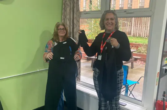 Two people hold up clothing 